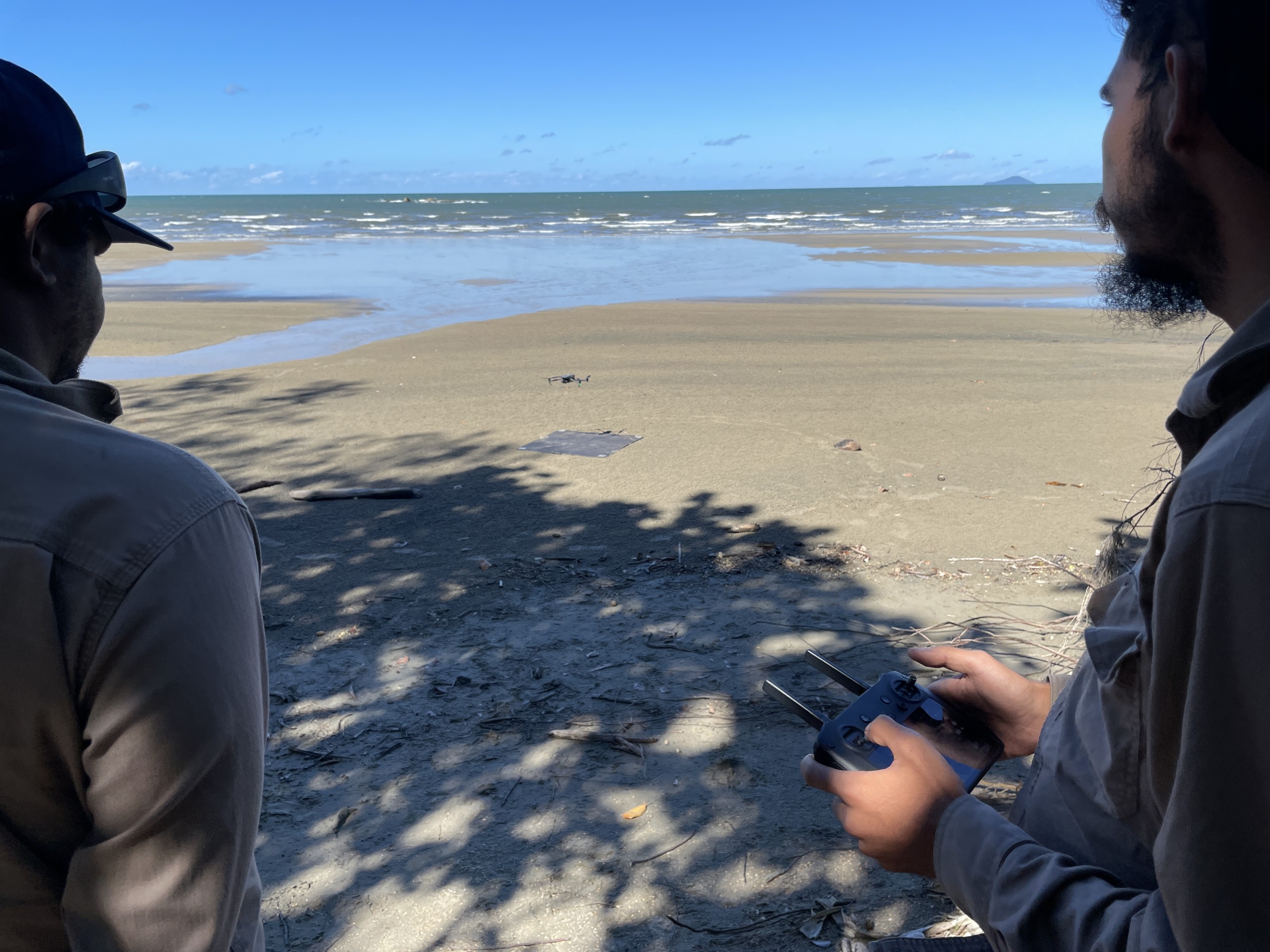 Two Aboriginal Rangers using a drone on a beach