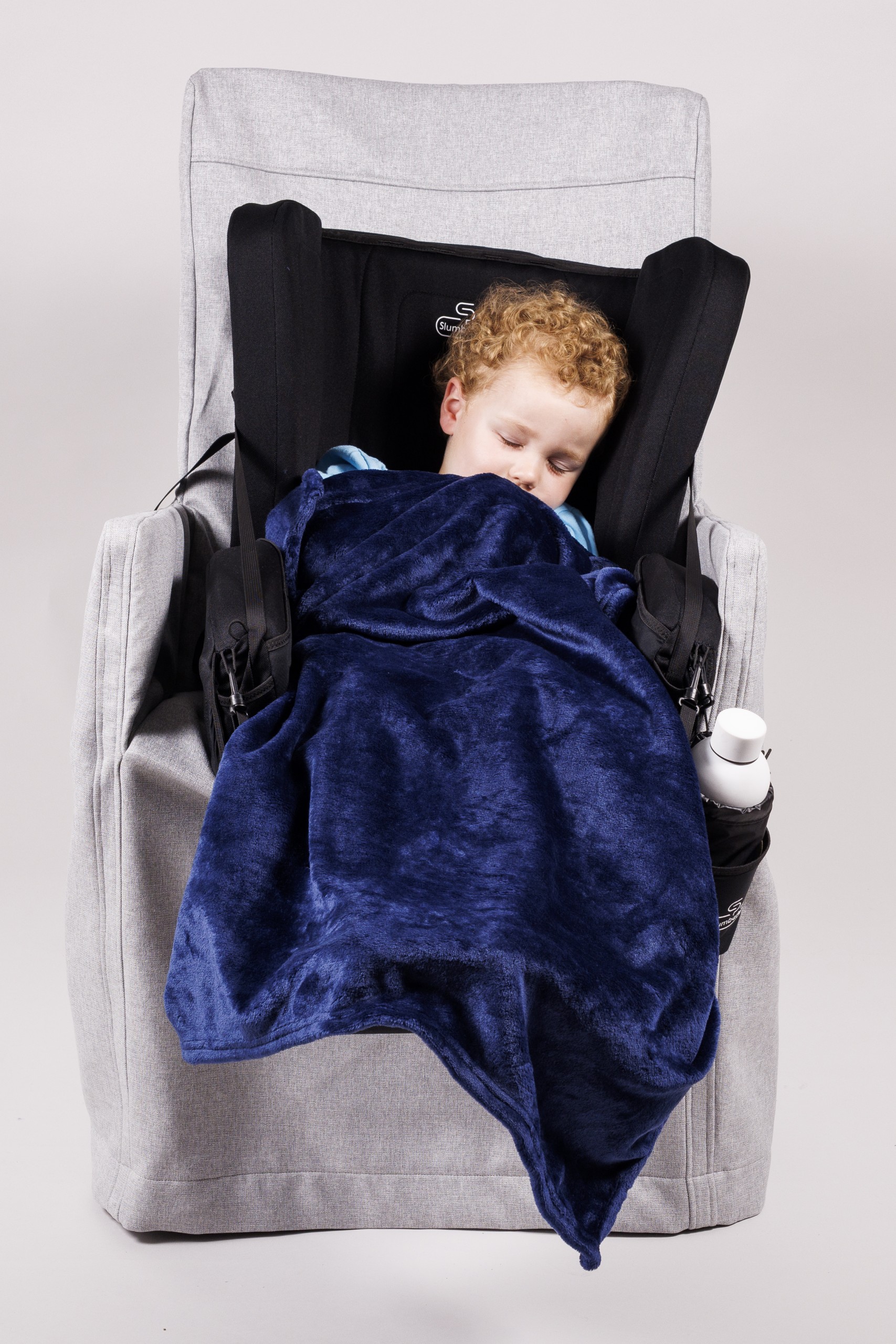 A child sleeps under a blanket in the SlumbaPak